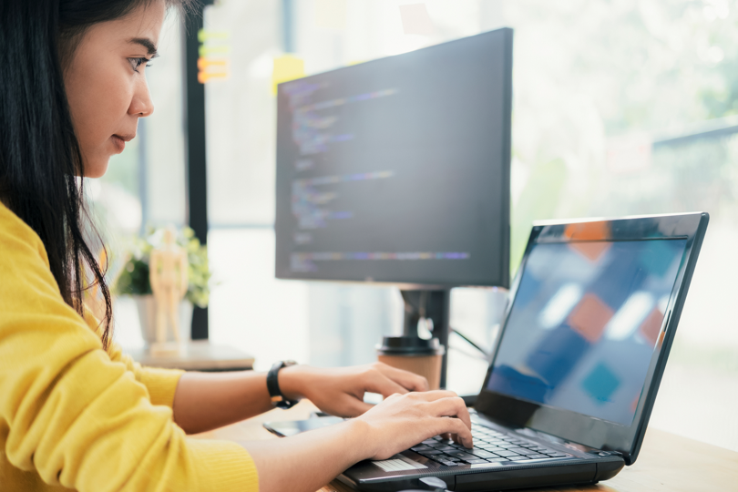 woman working from home on laptop with 2nd monitor